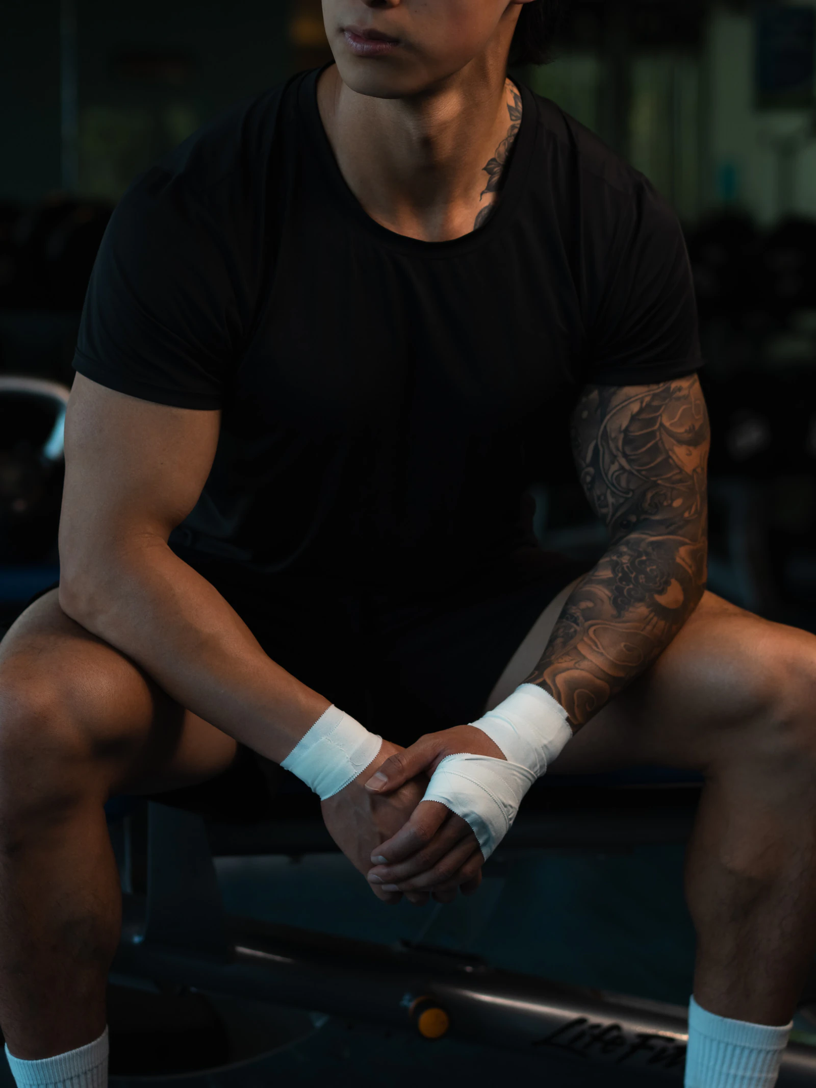 Athlete with both wrists taped, sitting on a gym bench