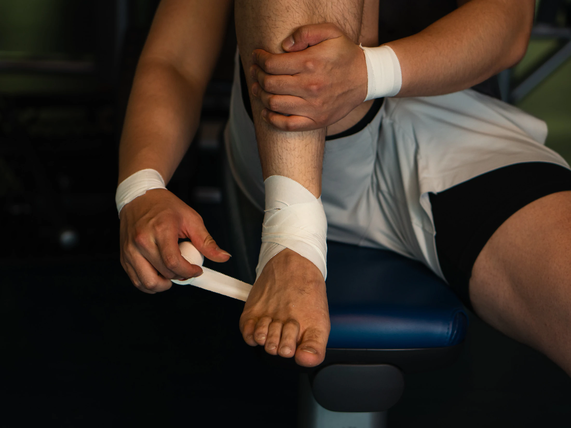 Athlete applying tape around an ankle